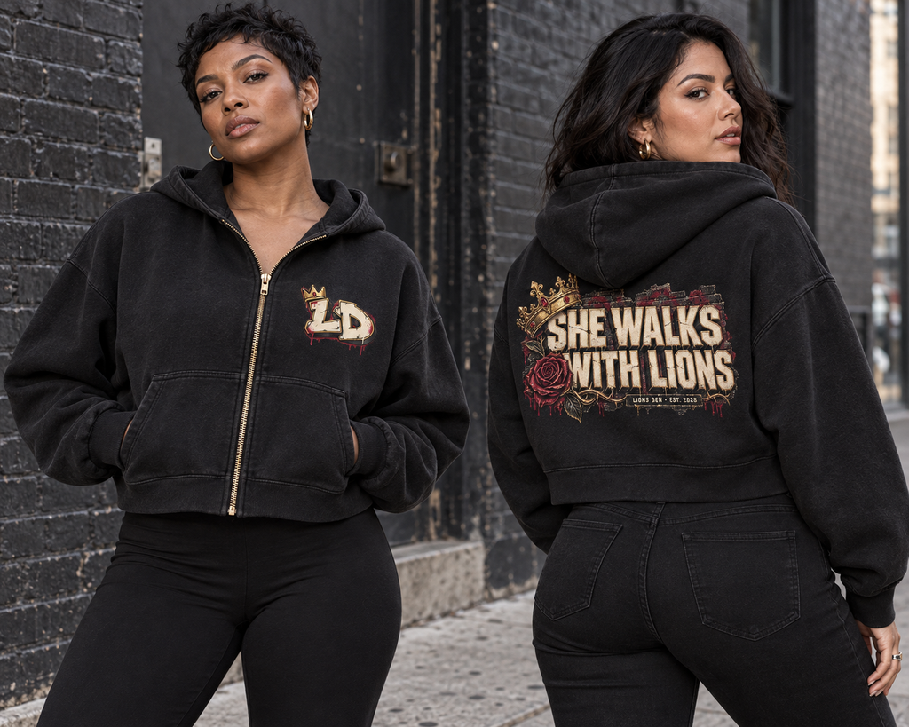 Two women modeling the Lions Den She Walks With Lions black boxy full-zip hoodie, showing front and back artwork
